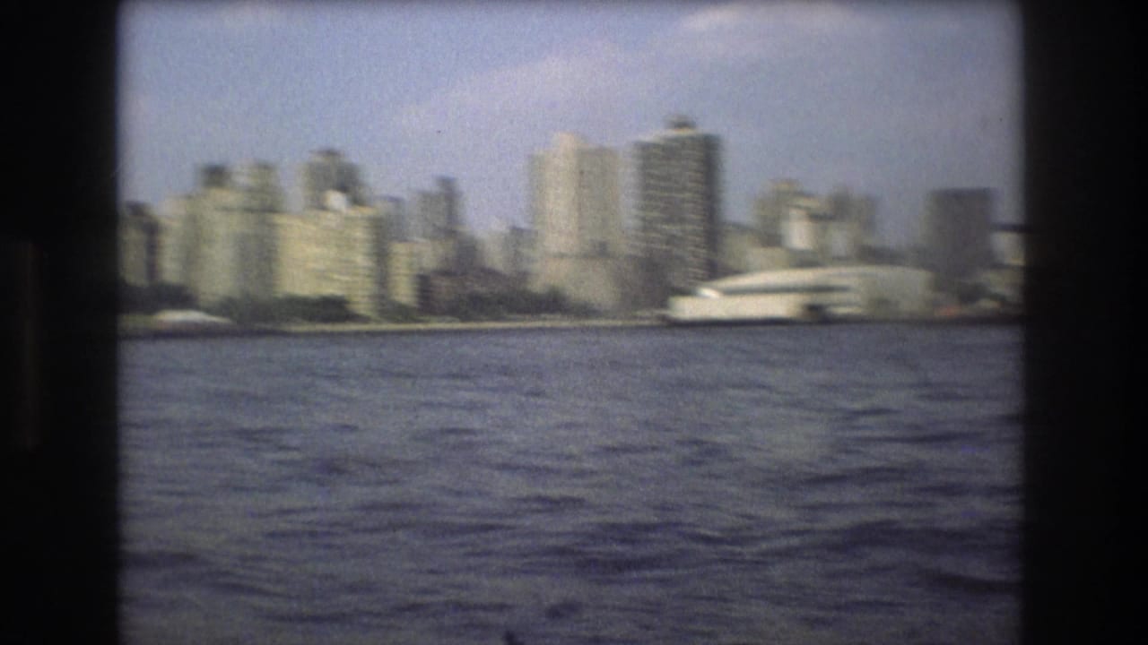 Waterfront skyline seen across harbor water under a pale sky.