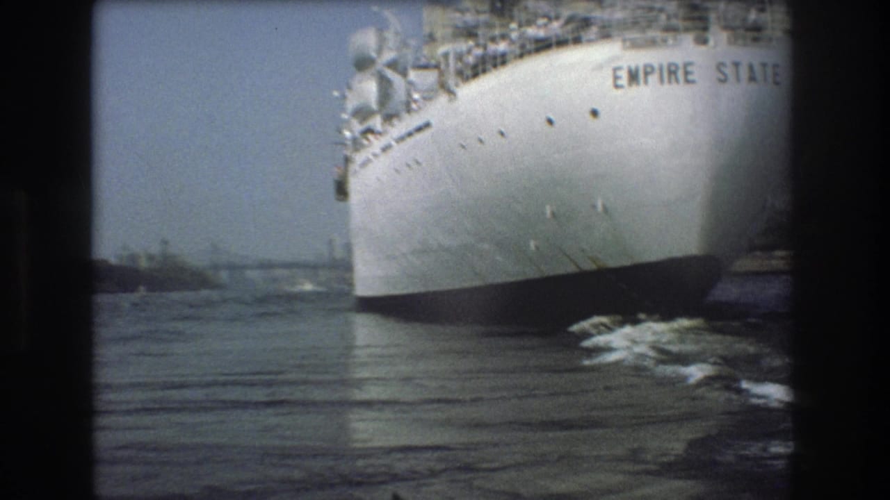 1975 Boston harbor frame with the Empire State name readable on the white hull as the vessel passes near the camera over rippled water.