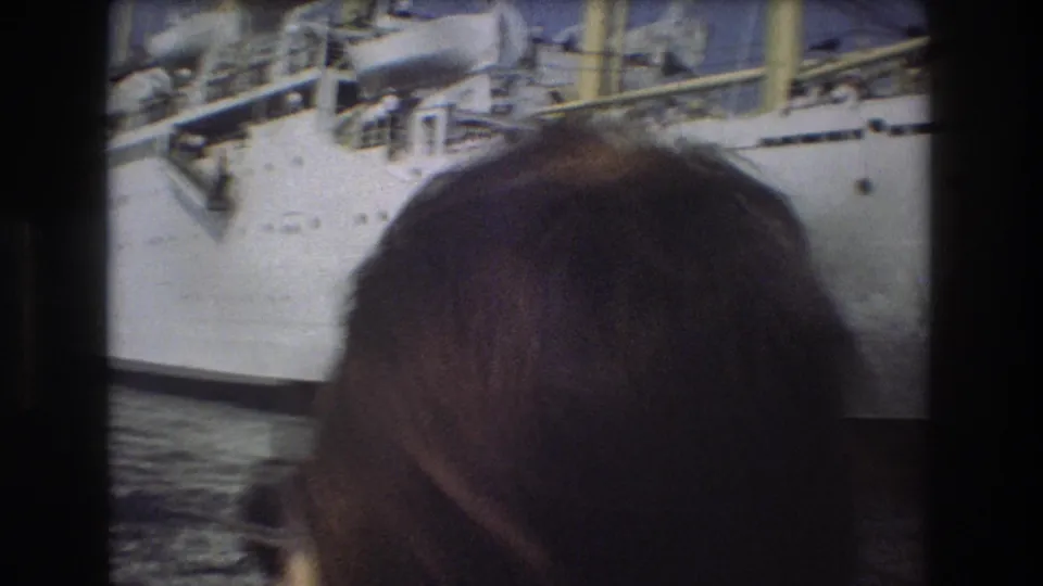 1975 Boston 8mm frame with a viewer's head in the foreground and the side of a large white passenger ship behind them.