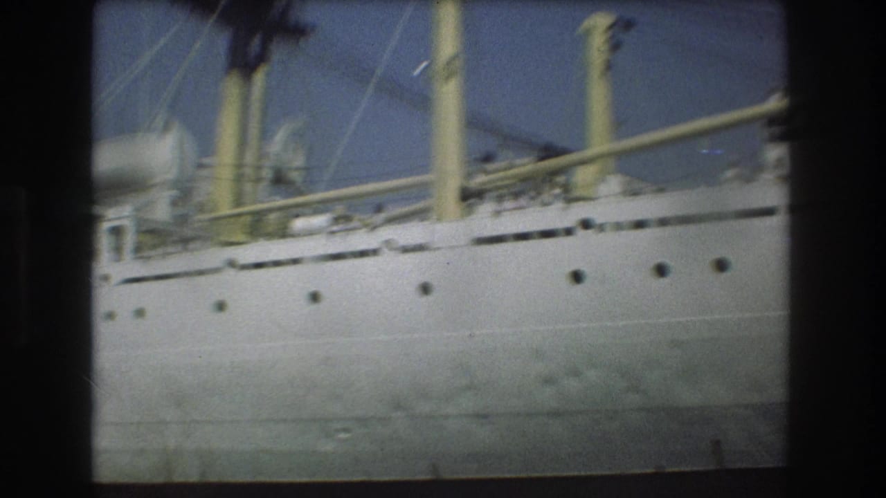 Close 8mm view of the passenger ship's white hull, yellow funnels, railings, and upper deck details in Boston harbor footage from 1975.