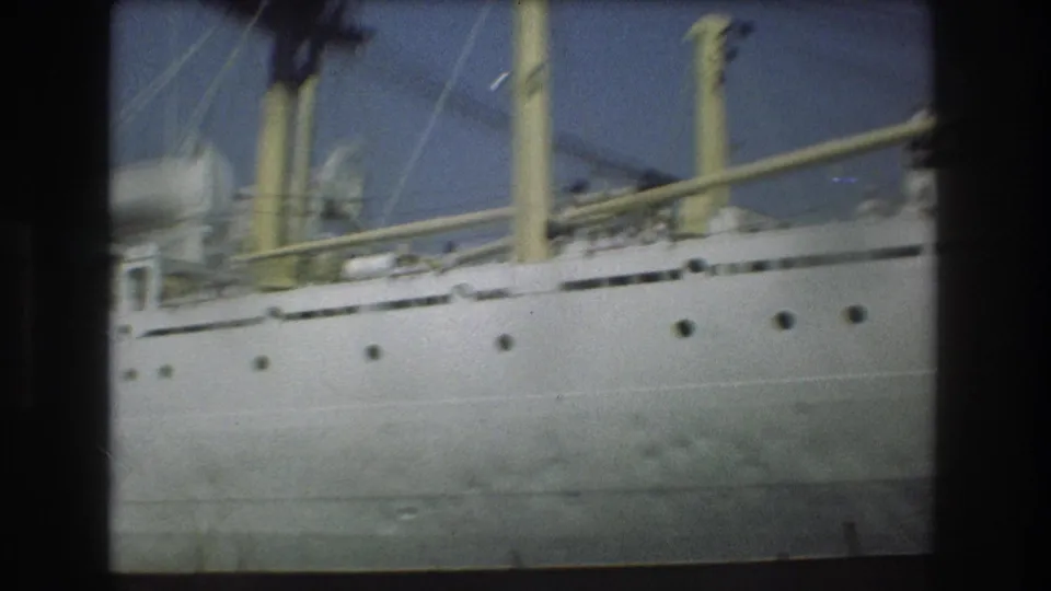 Close 8mm view of the passenger ship's white hull, yellow funnels, railings, and upper deck details in Boston harbor footage from 1975.