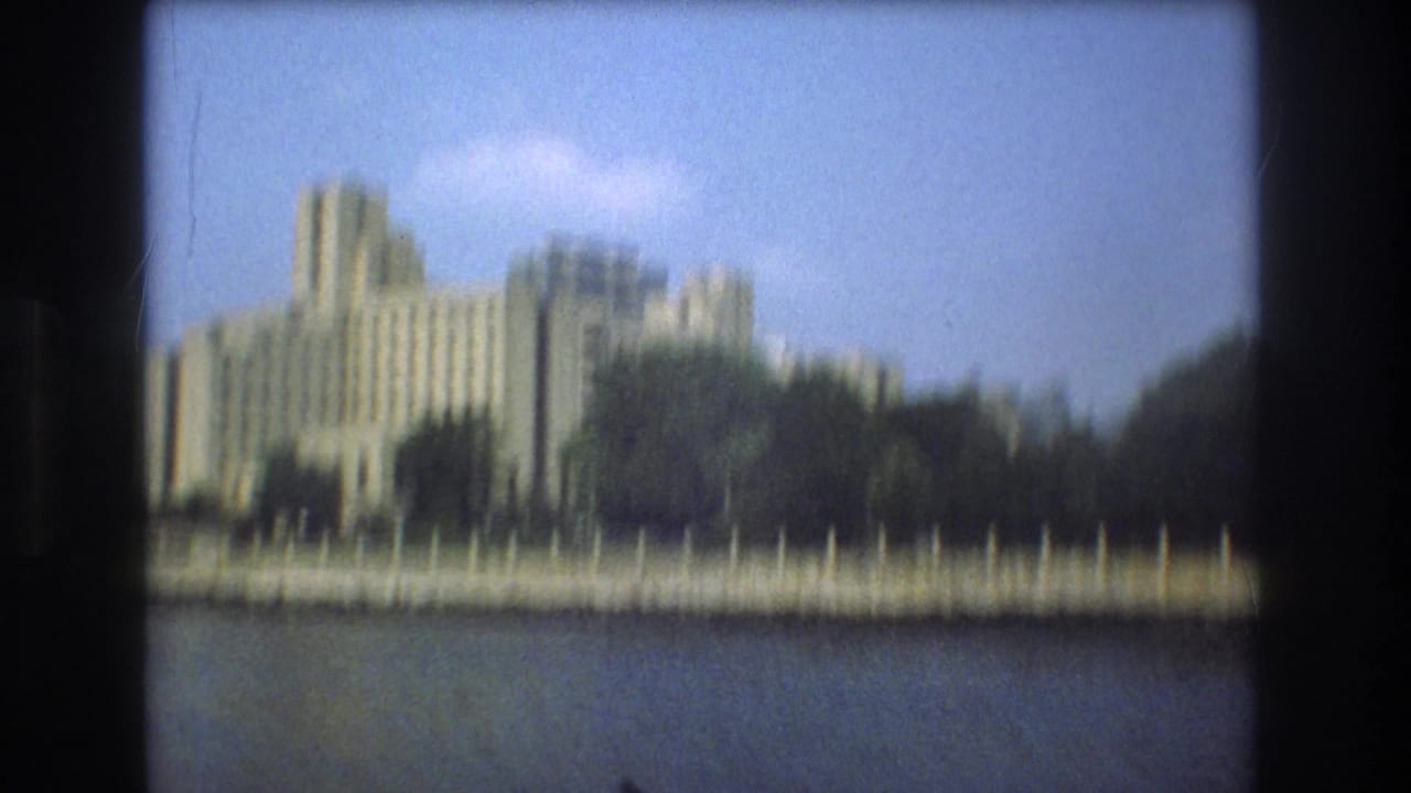 Soft-focus waterfront building and trees viewed across water.