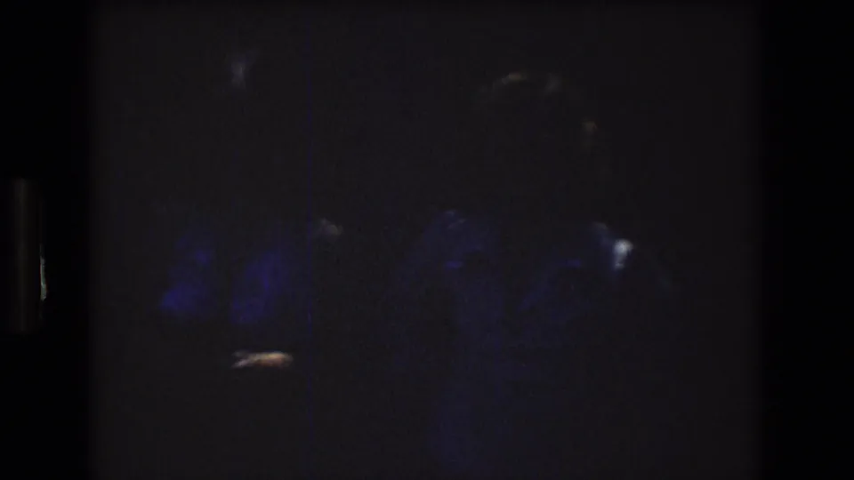 Dark transitional 8mm frame in the Mt Bromley home movie, showing faint blue areas, scattered highlights, grain, and little clearly identifiable detail.