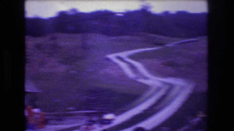 At Mt Bromley, Vermont in 1976, a cart blurs near the lower curve of the hillside slide, emphasizing the motion of the amusement ride on the grassy slope.