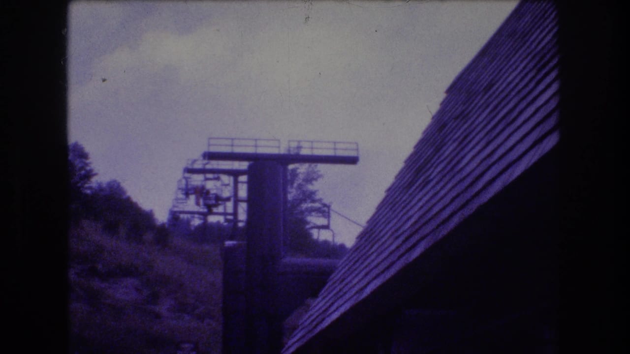 Ski lift tower and roofline seen through a purple-tinted 8mm frame.