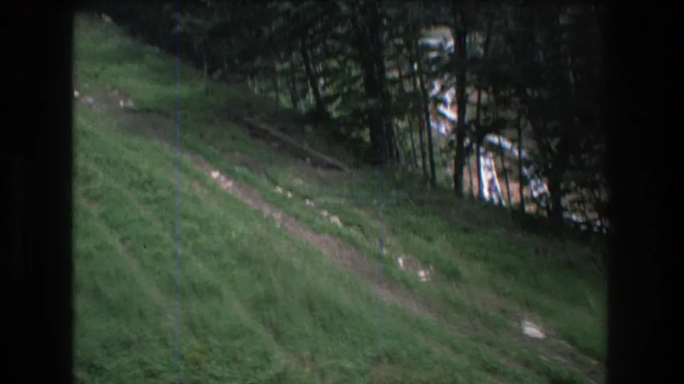 1976 Mt Bromley, Vermont 8mm frame with a terraced dirt path cutting across a grassy slope and darker conifer growth in the background.