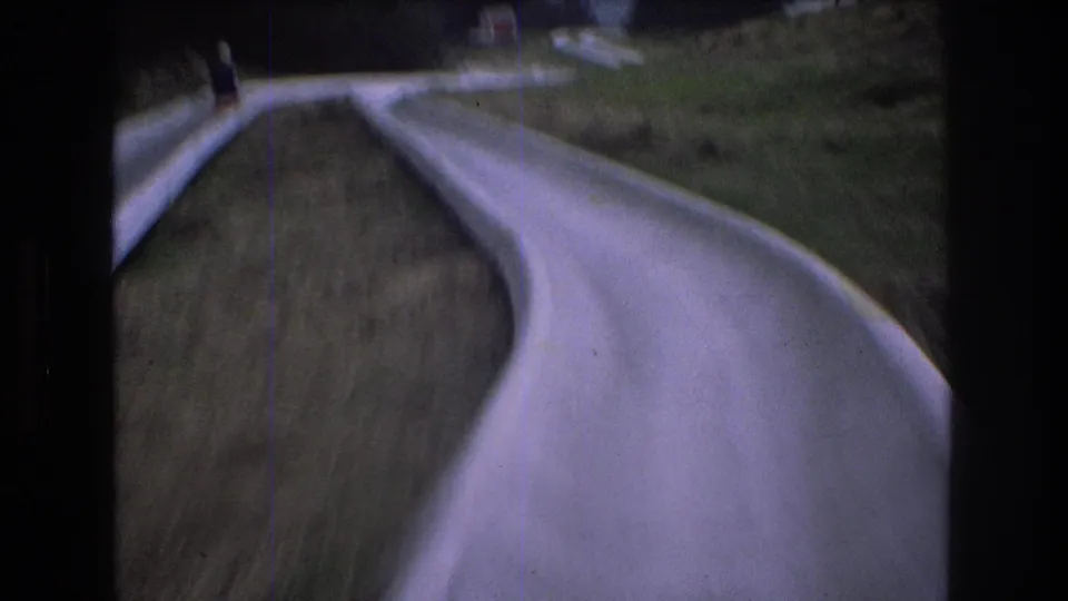 A motion-blurred 8mm frame captures the rider’s point of view as the pale alpine slide drops through a narrow grassy section at Mt. Bromley.