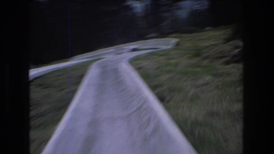 The final frame shows a blurred rider's-eye view of the concrete luge-style chute curving through the grassy Mt Bromley hillside with trees beyond.