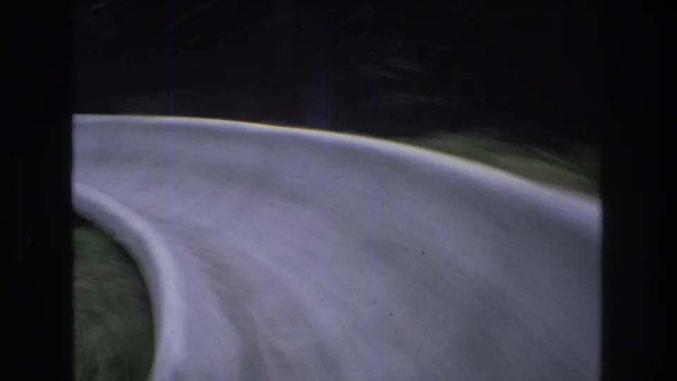 1976 Mt Bromley, Vermont 8mm frame showing the alpine slide trough sweeping across the foreground during a fast turn, with grass and dark trees in the background.