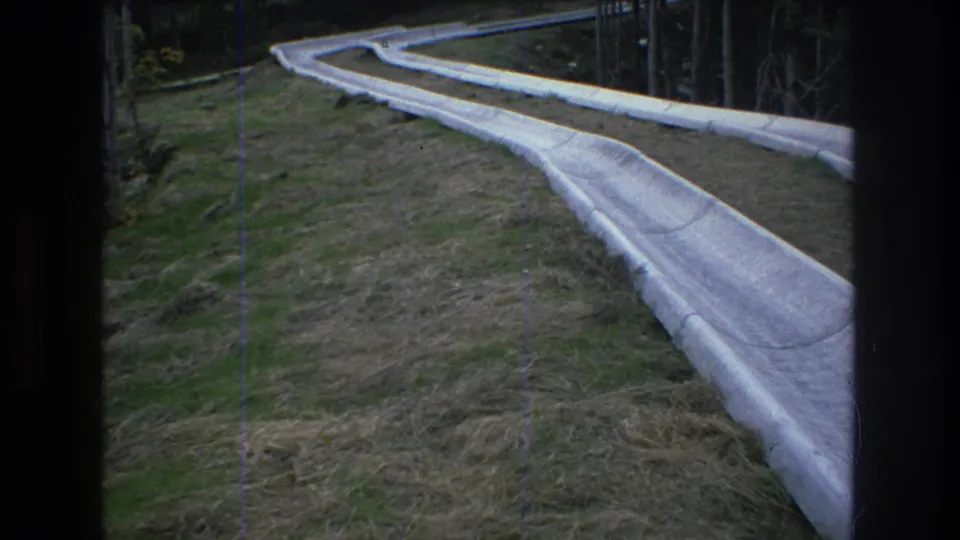 1976 Mt Bromley 8mm frame showing a white molded slide curving downhill through dry grass and trees.