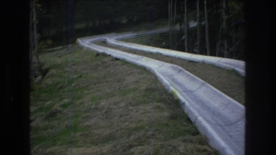 1976 Mt Bromley frame showing the white slide extending across the hillside with trees and patchy grass around it.