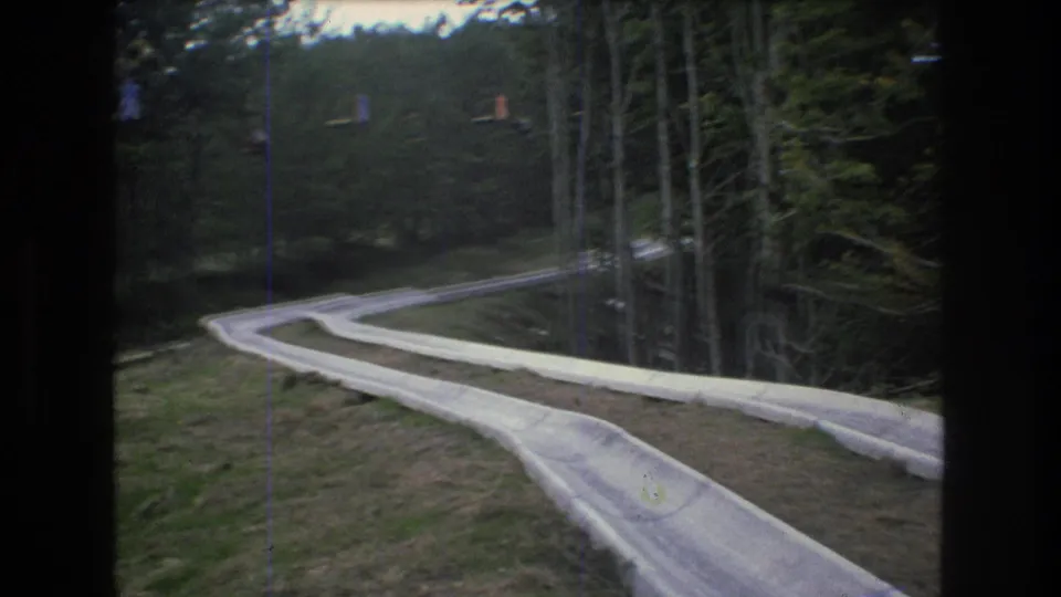 1976 Mt Bromley, Vermont 8mm frame showing a winding track through trees, with faint distant resort features on the slope.