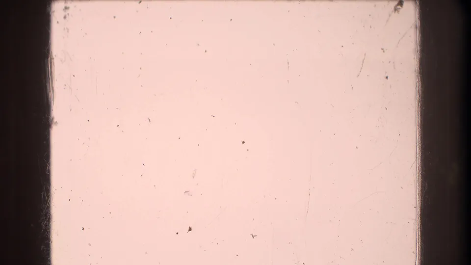 A pink 8mm frame from the supplied Mt Bromley clip showing film gate edges, dust, and scratches rather than a readable outdoor scene.