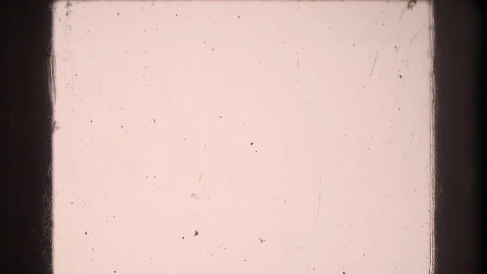 The final frame is largely pink and overexposed, with 8mm gate edges, scattered dust, and scratches visible across the film surface.