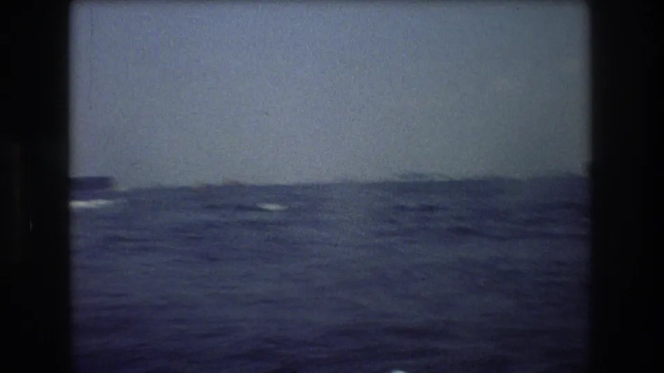 1976 8mm frame showing choppy open water and a hazy horizon, with only faint distant shapes visible and no people or identifiable markings.