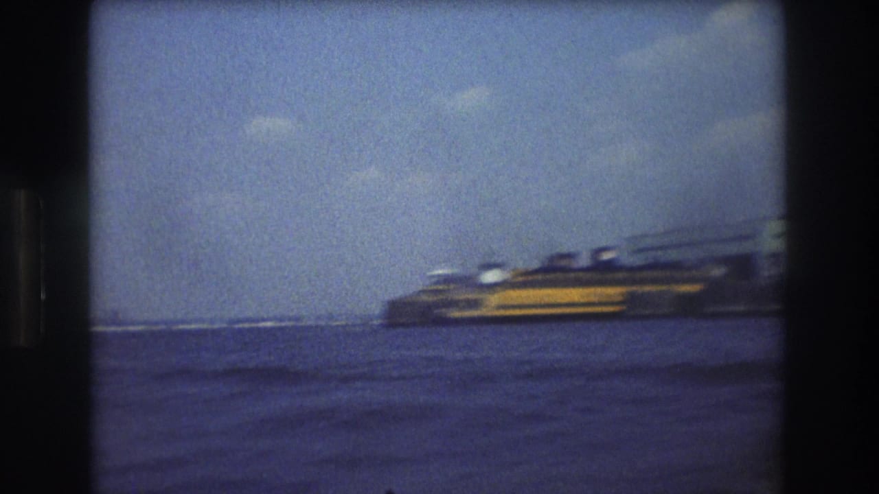 Ferry-like vessel near the right side of the frame on open water beneath a blue sky.