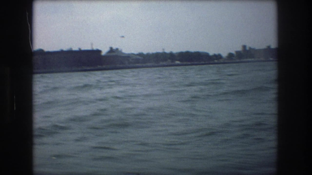 Water stretches toward a low shoreline with buildings and trees in the distance.
