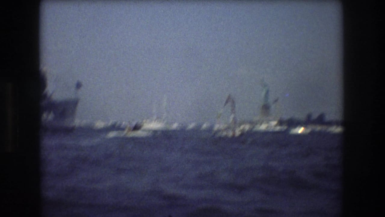 Sailboats and harbor craft on hazy water.