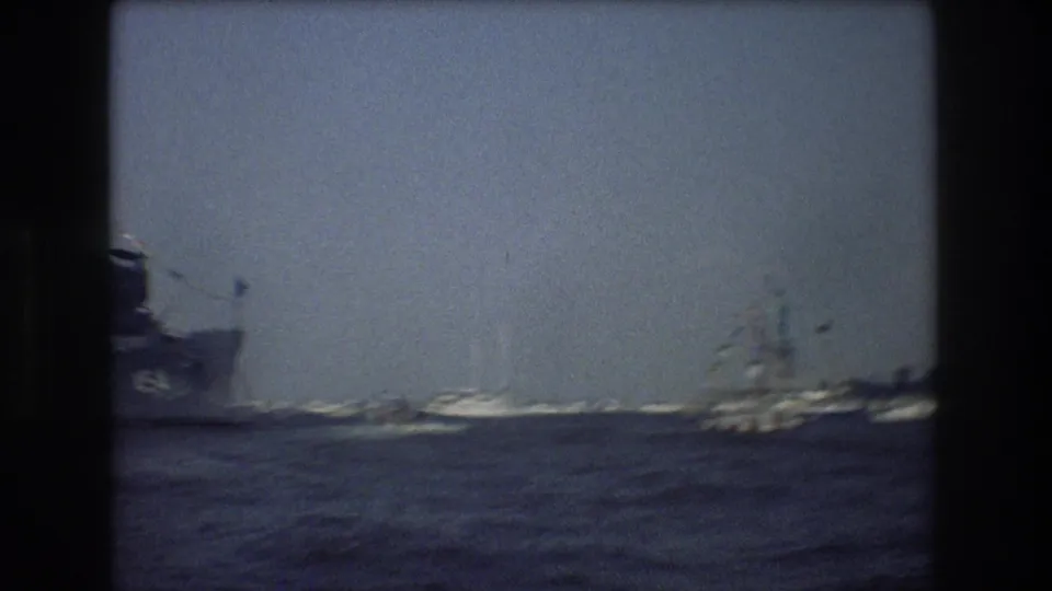 The Statue of Liberty appears in the hazy distance beyond sailboats and harbor water in 1976 New York City home-movie footage.