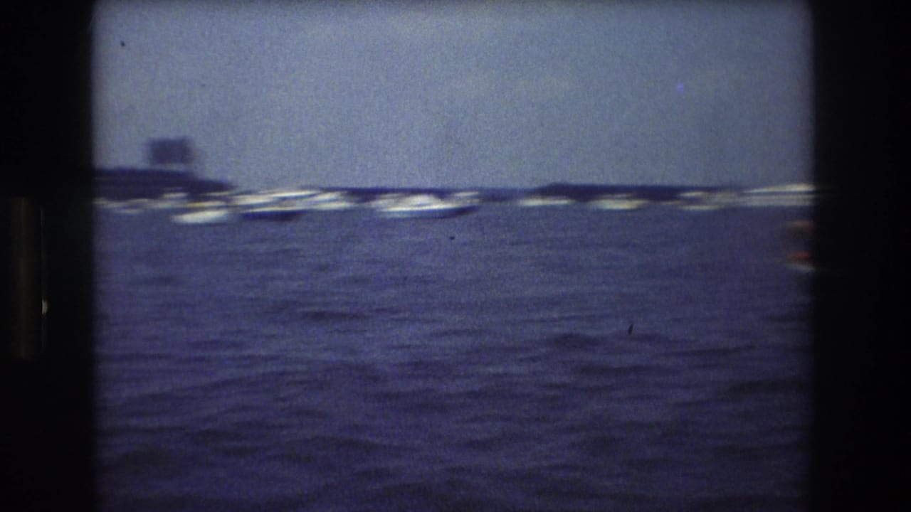 Open water with a line of distant boats and a dark shoreline shape beyond them.