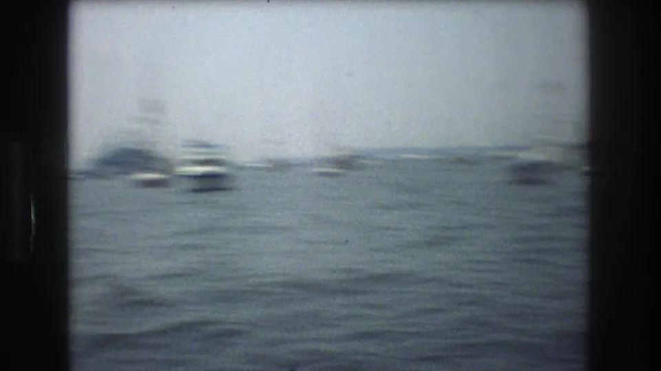 1976 New York City 8mm frame with boats scattered across gray-blue water, softened by motion blur and visible film grain.