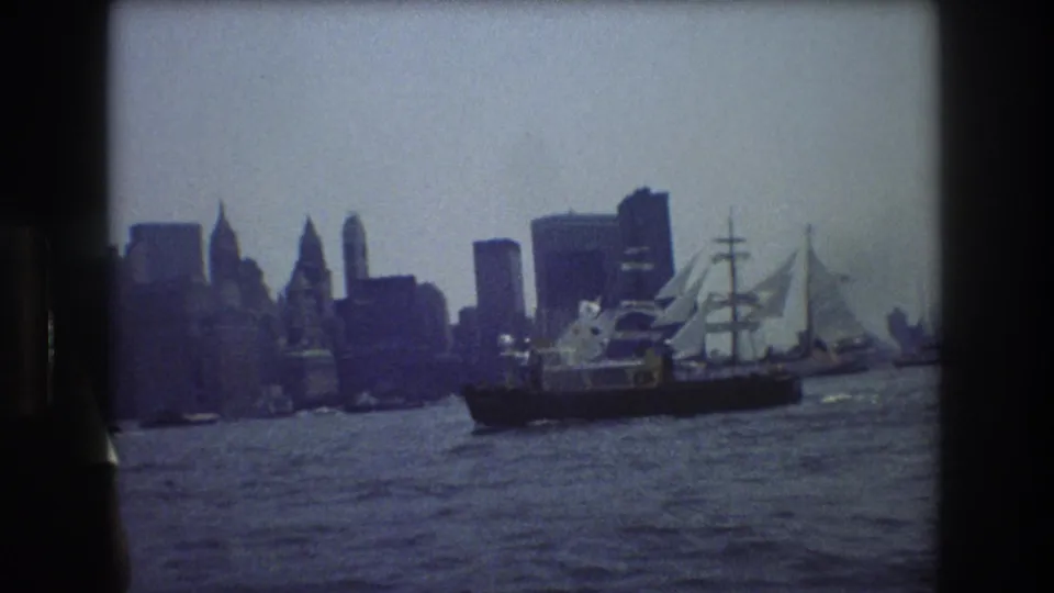 A clearer 1976 harbor frame shows the multi-masted ship on choppy water with the New York City skyline rising behind it.