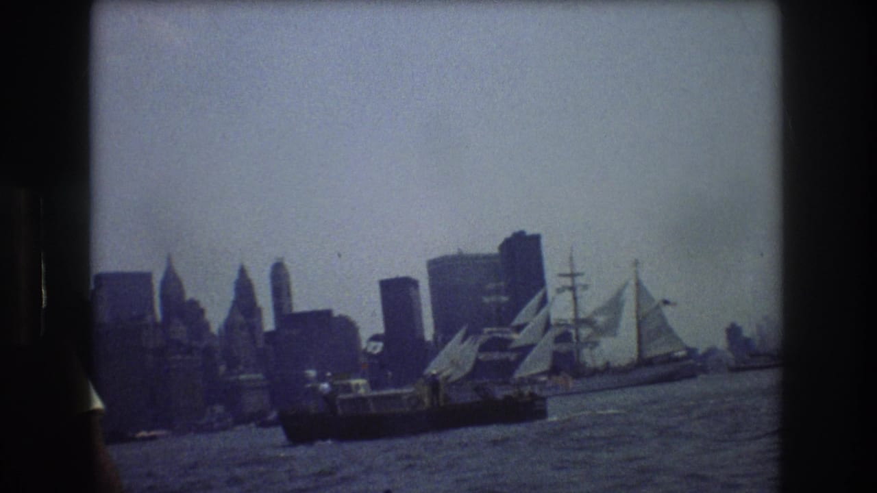 A handheld 8mm view of a tall sailing vessel on New York Harbor, with the city skyline in the background and dark film gate edges visible.
