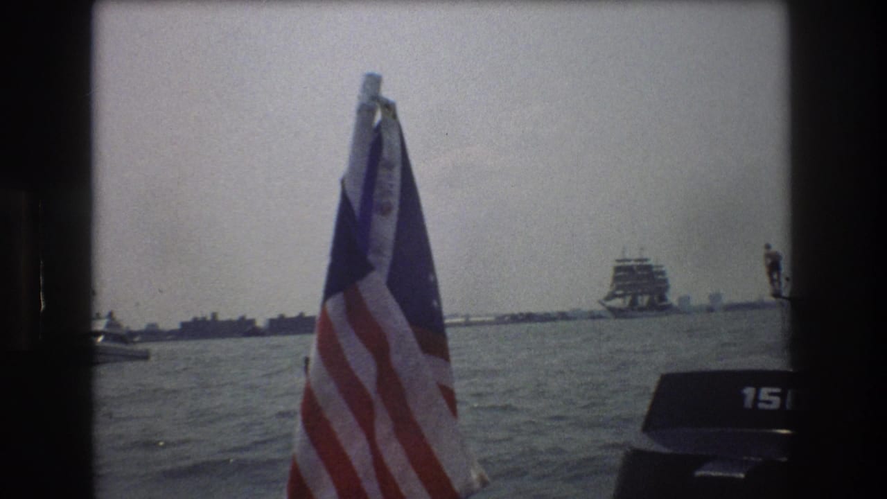 American flag on a boat with open water and a distant vessel in the background.