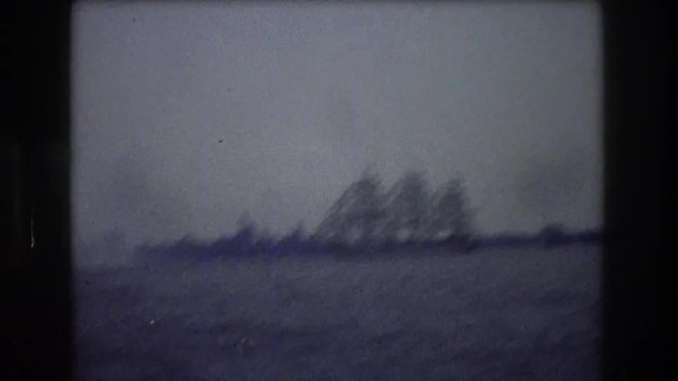Soft, motion-blurred 8mm frame from the 1976 New York City clip showing a distant three-masted sailing ship across open water.