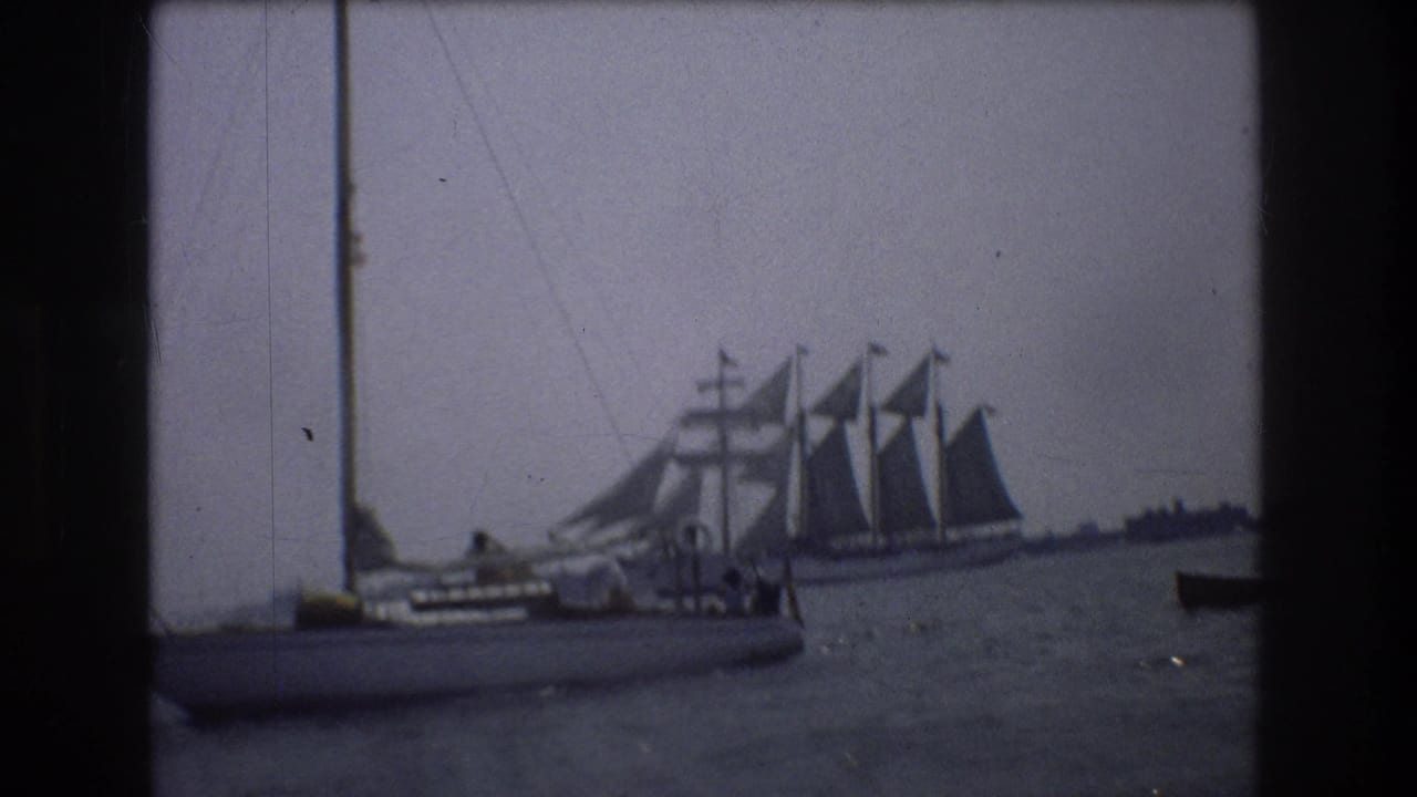 Foreground sailboat and distant multi-masted vessel on open water.