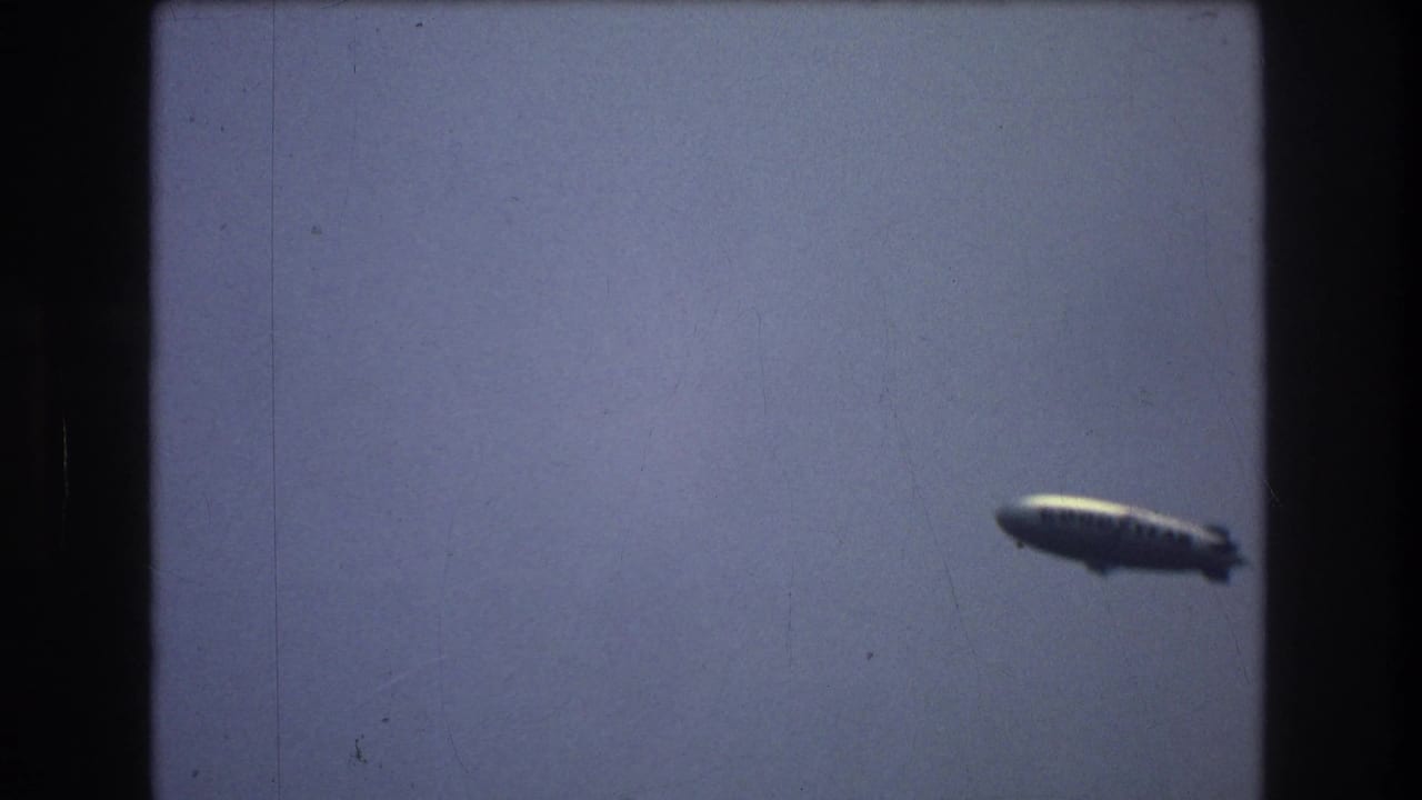 Distant airship moving across a pale sky.