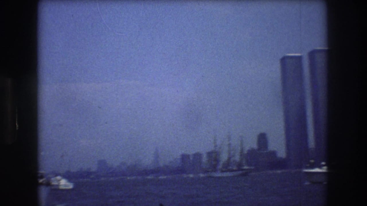 Manhattan skyline with the Twin Towers rising beside harbor water and boats.
