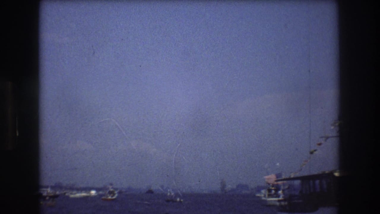 Small boats scattered across open harbor water with a pier or vessel edge at right.