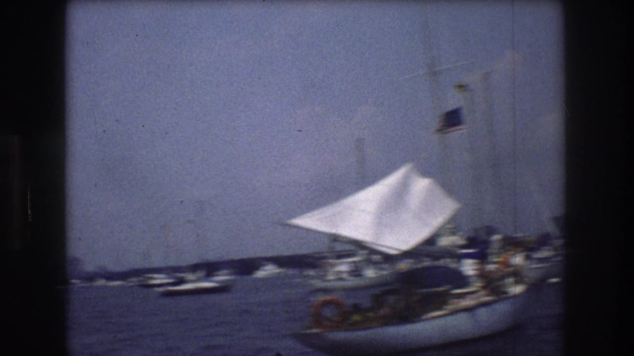 Sailboat and small boats on New York Harbor with skyline in the distance.