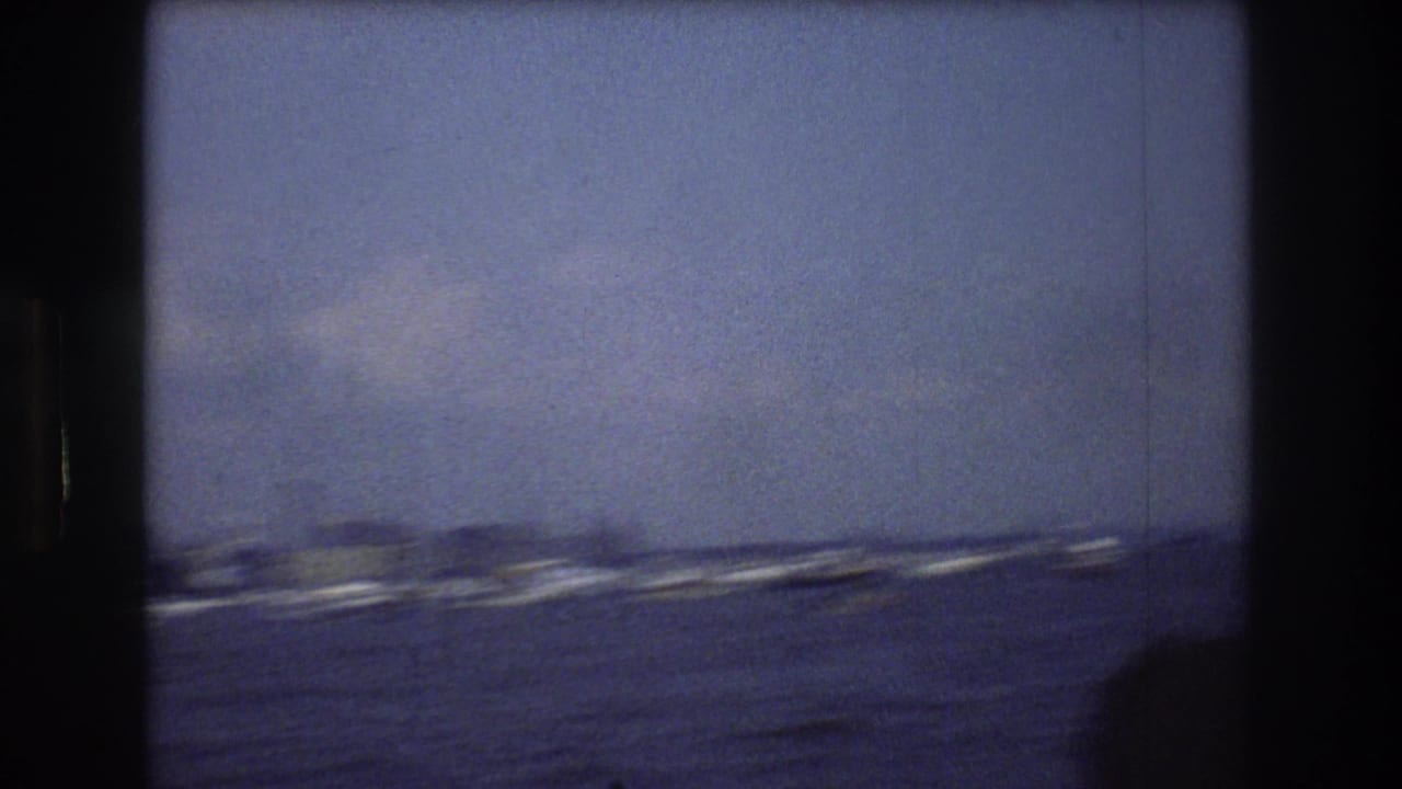 Open harbor water with distant boats and a hazy shoreline.