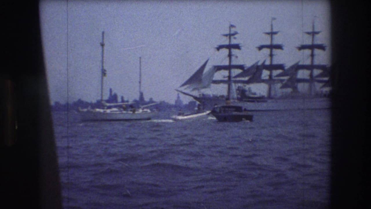 1976 New York City harbor view with a large multi-masted sailing ship, a small motorboat, and sailboats seen through an 8mm film frame.