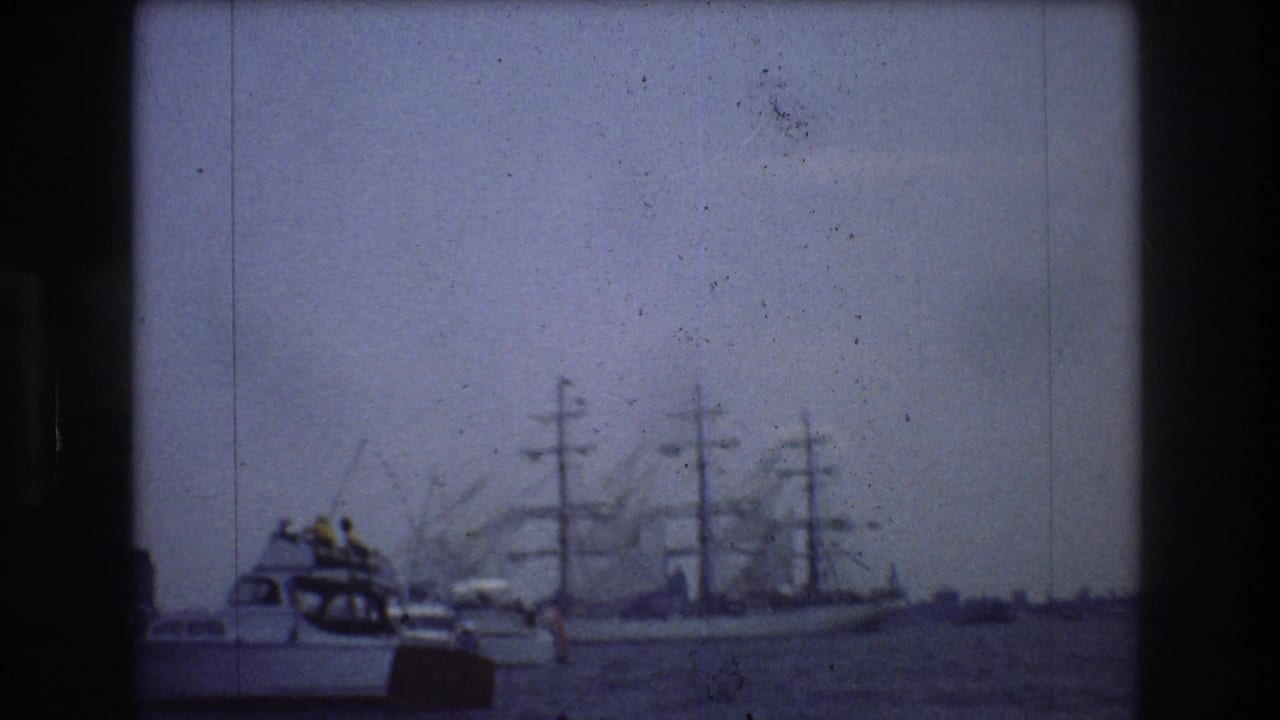 Small motorboat and large sailing ship on hazy harbor water.