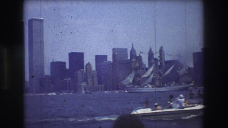 Lower Manhattan and the World Trade Center towers appear across the water as boats pass in the foreground in a 1976 New York City harbor home movie.