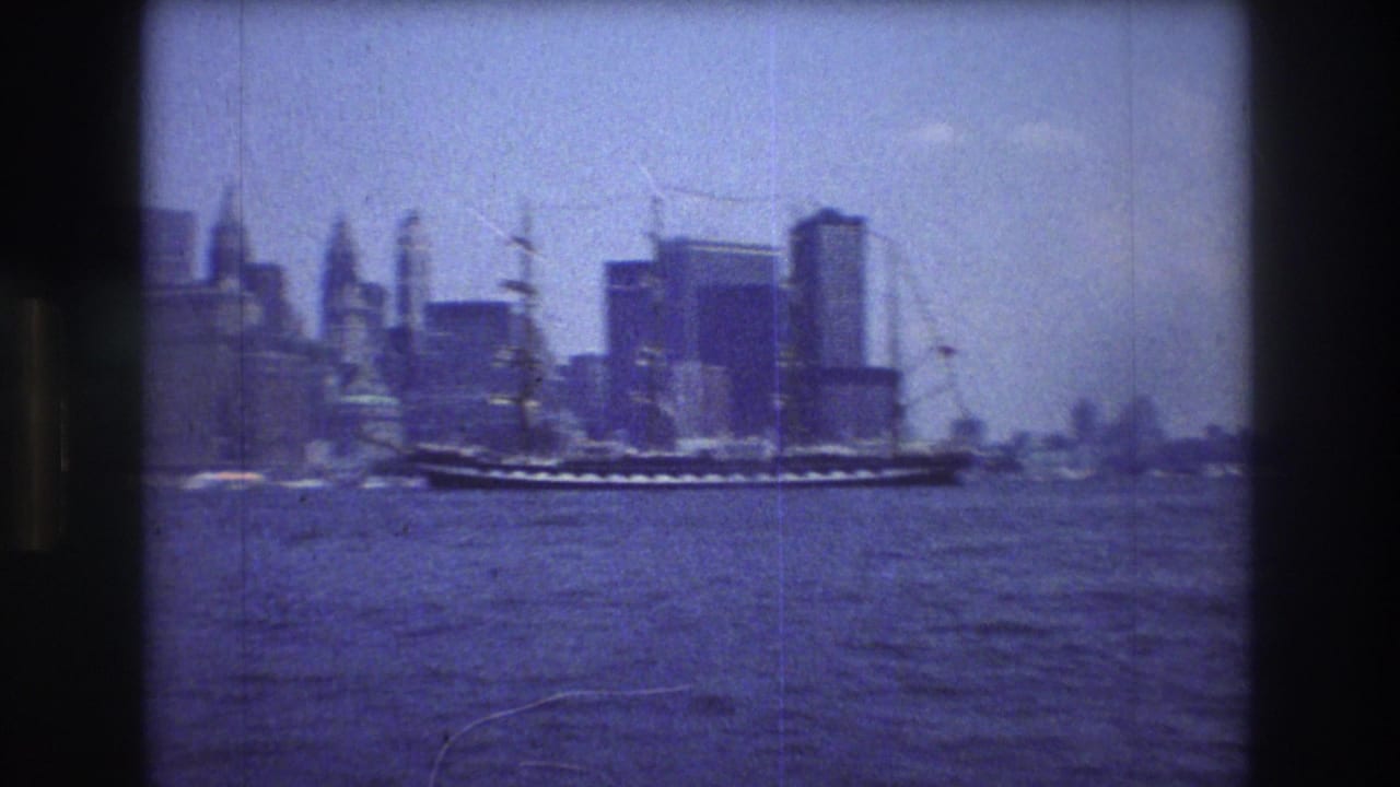 A multi-masted sailing ship moves across New York City harbor water with the Manhattan skyline in the background in metadata-supported 1976 8mm footage.