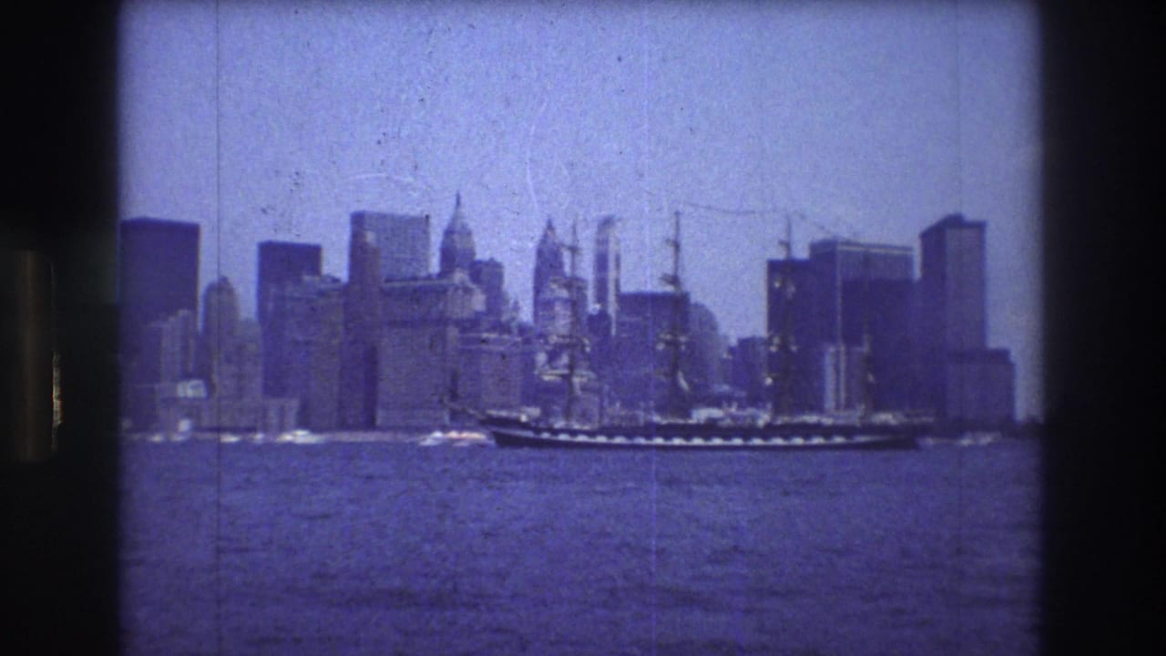 The tall ship appears mid-frame on the river, with New York City high-rises and waterfront buildings visible behind it in blue-tinted 8mm footage.