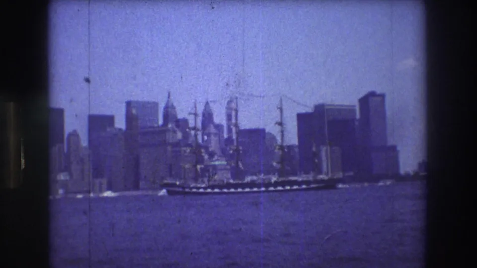 The ship appears farther along its crossing in front of New York City's skyline, with water, high-rises, and visible 8mm film wear in the frame.