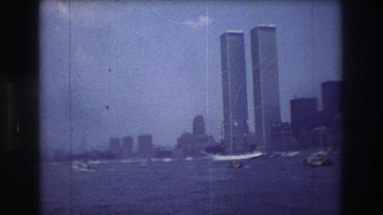 Distant Manhattan skyline with the Twin Towers rising above water and small boats.