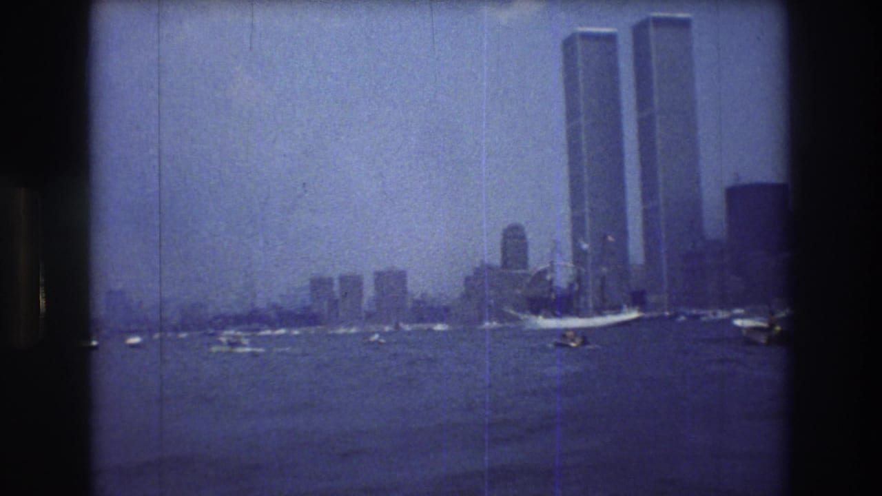 Wide 1976 New York City harbor view with the World Trade Center towers on the skyline and several boats crossing the water.