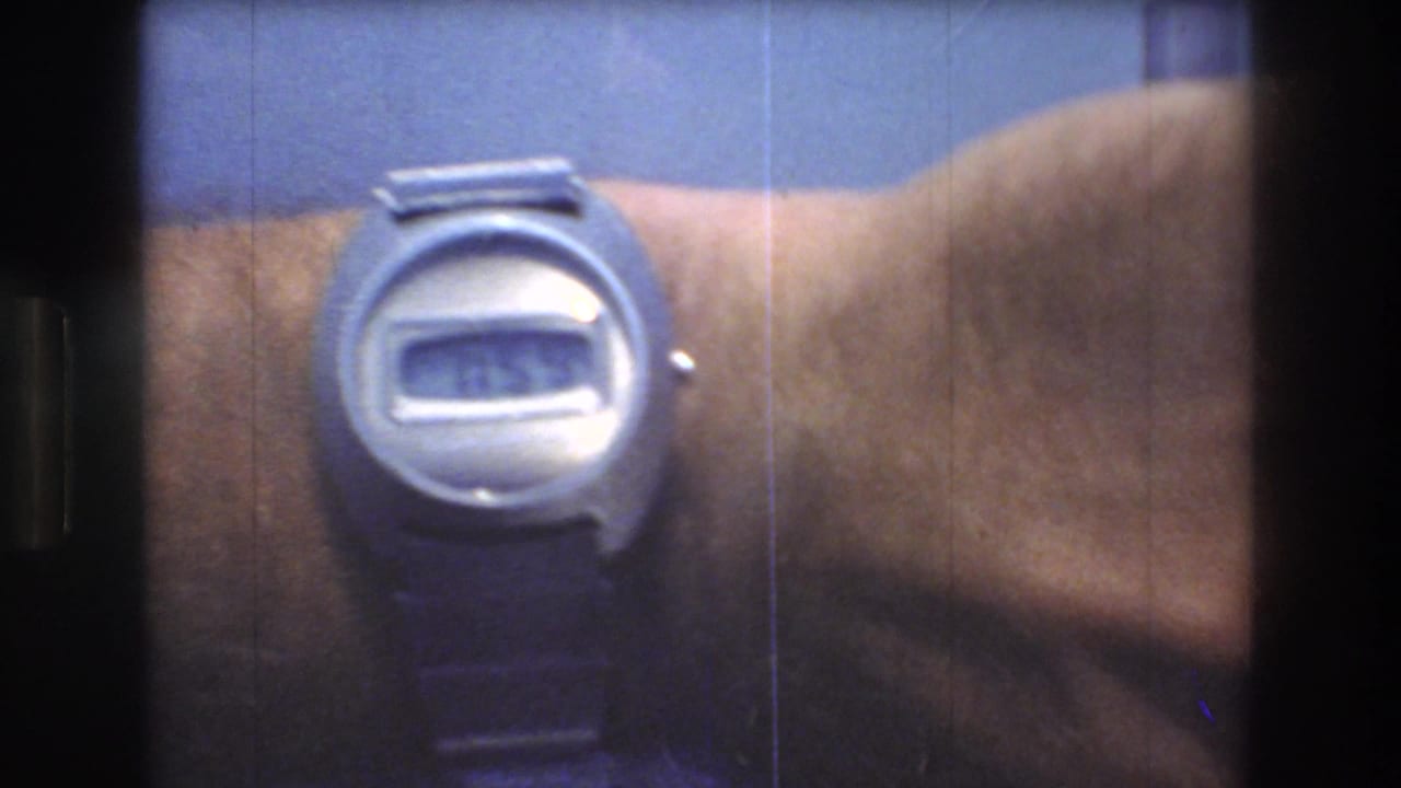 Silver digital wristwatch on a man's wrist, partially soft in focus.