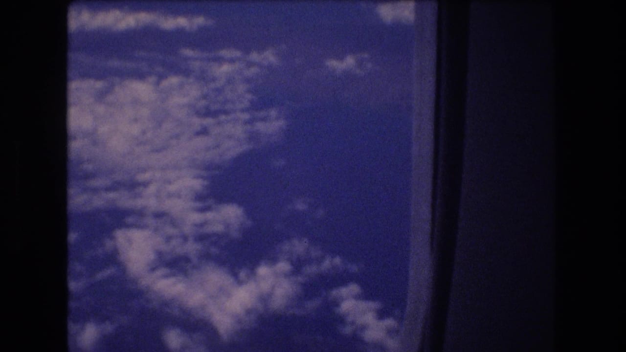 High-altitude cloud formations framed by a dark aircraft window.