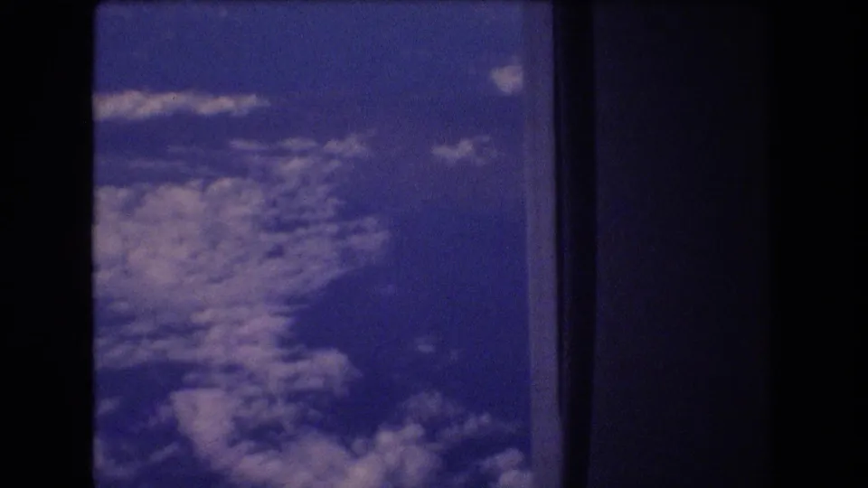 Final frame shows a blue-tinted aerial cloud view with dark aircraft-window or film-edge framing, consistent with 1977 8mm home-movie travel footage.