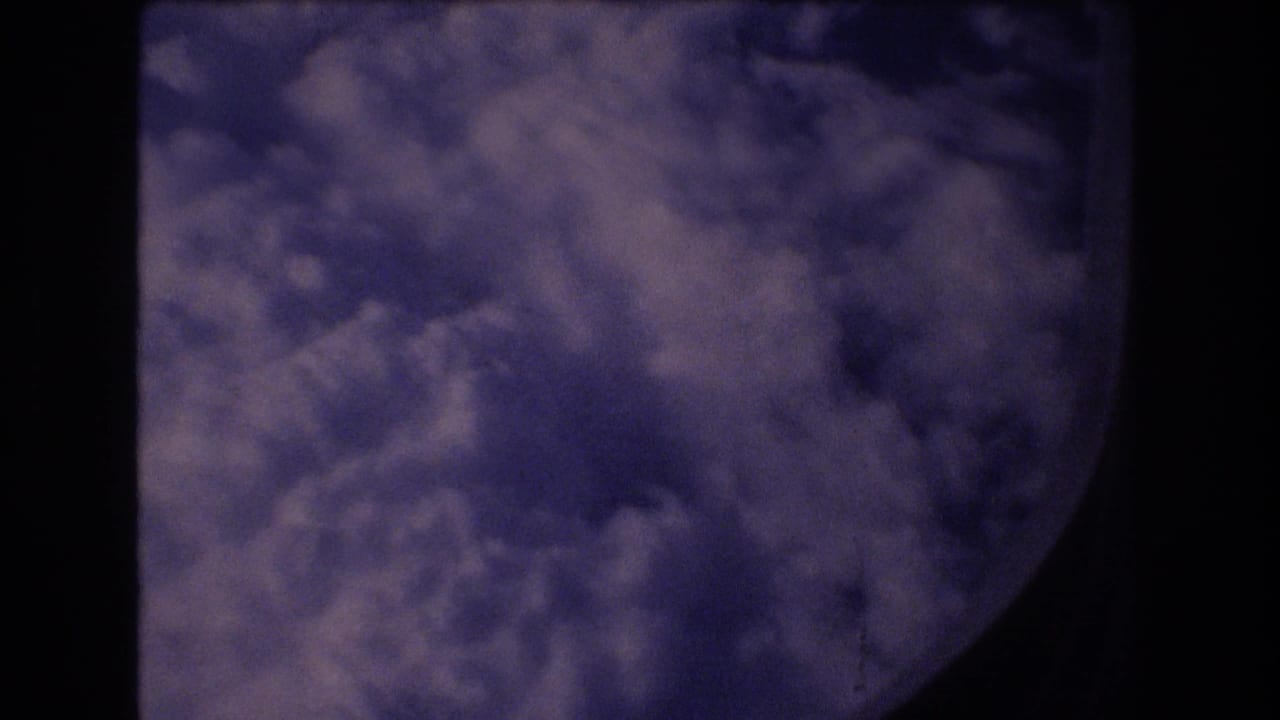 Dense clouds outside an airplane window with dark framing at the edges.