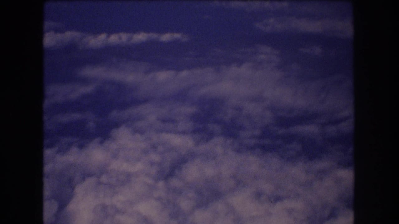 Blue sky and cloud tops framed by the airplane window edge.
