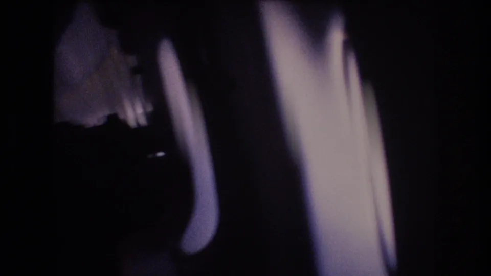 The final 8mm frame shifts toward a dark airplane interior edge or window-side structure, with blue-toned clouds still visible beyond the window area.