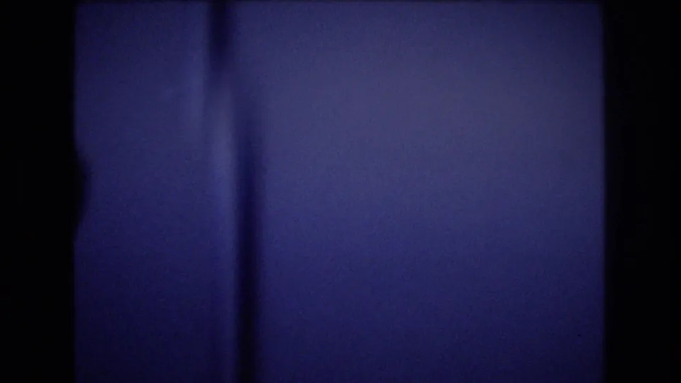 Soft, blue-tinted 8mm frame showing a close, abstracted view of an airplane interior surface during the cabin sequence.